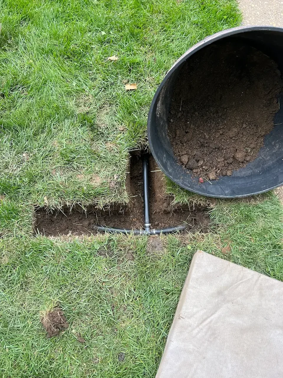 Open lawn trench with sprinkler pipe being installed