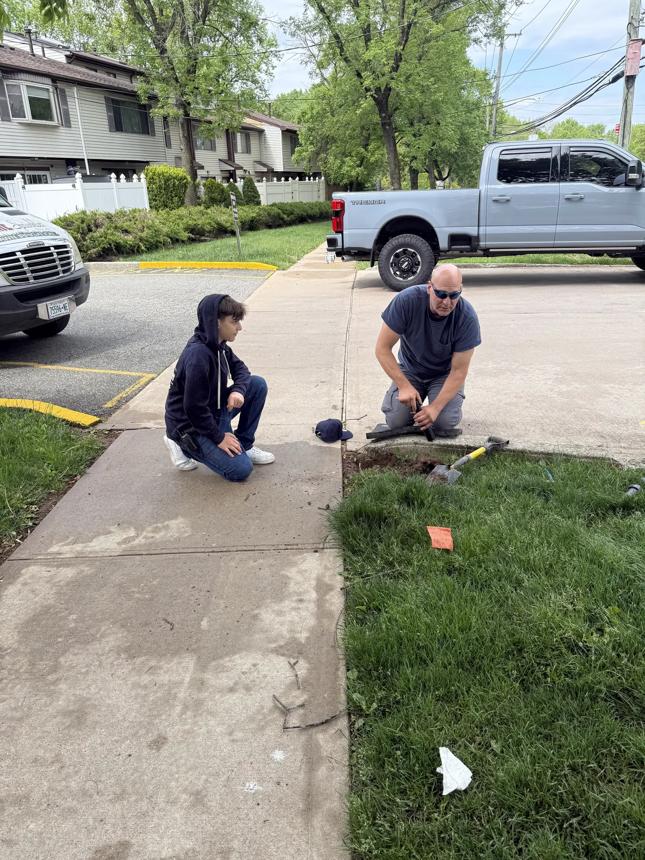 Prime Sprinkler technicians working beside a sidewalk during sprinkler installation