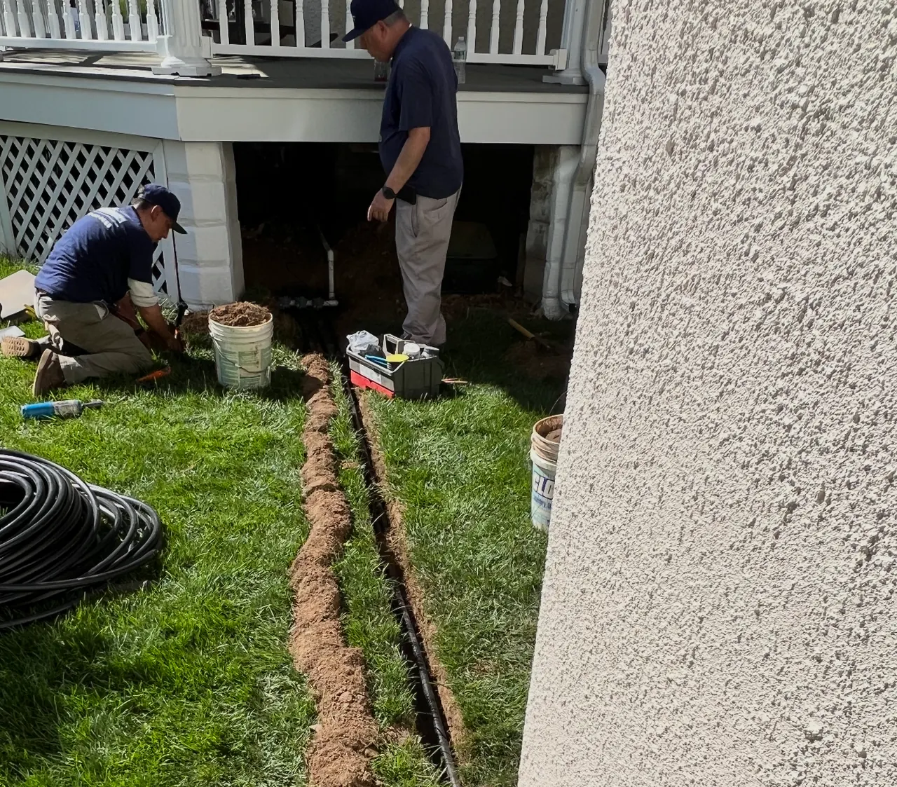 Prime Sprinkler crew installing irrigation pipe in a lawn trench