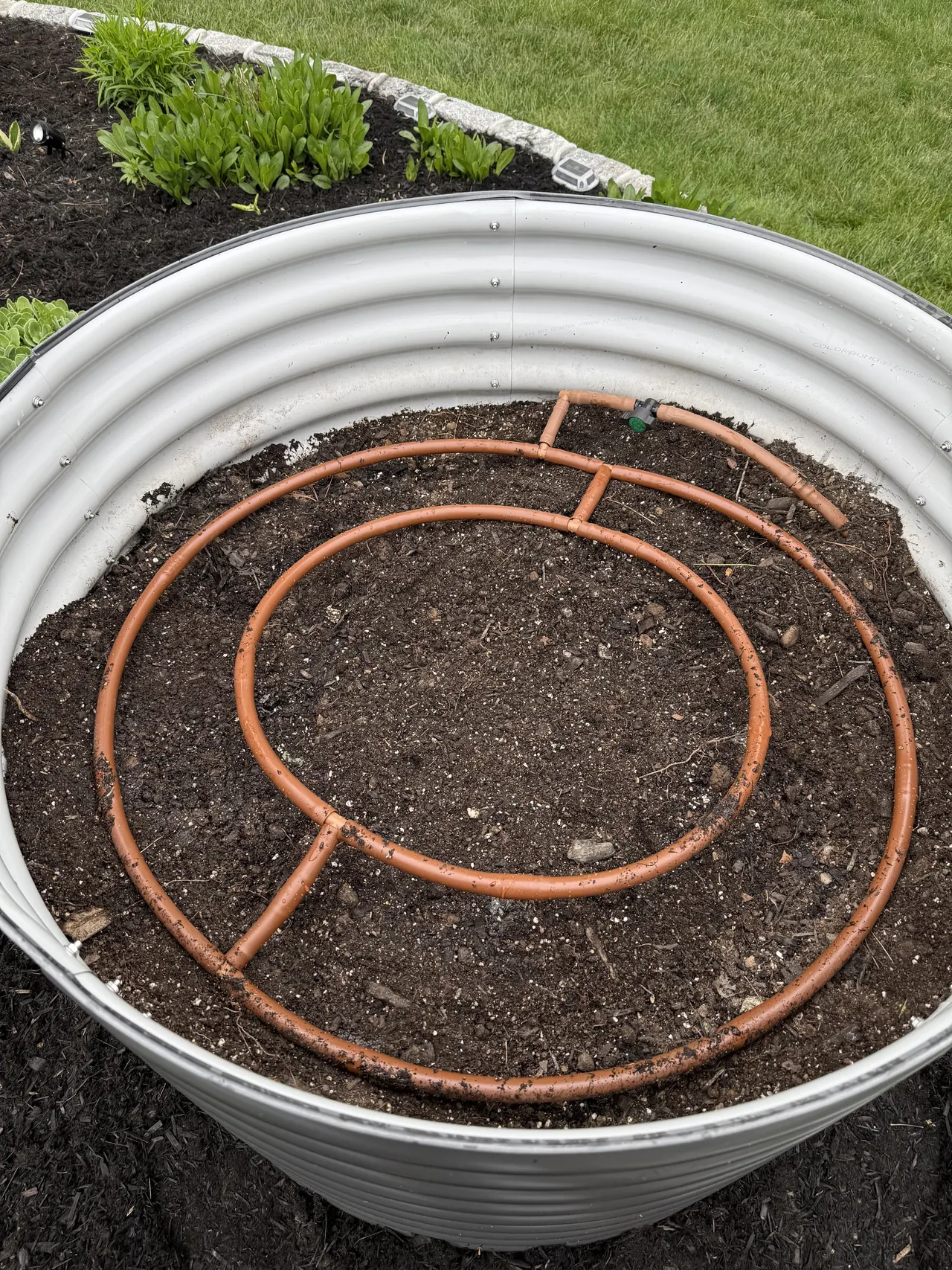 Sprinkler installation detail showing pipe layout and fresh trench work beside a lawn