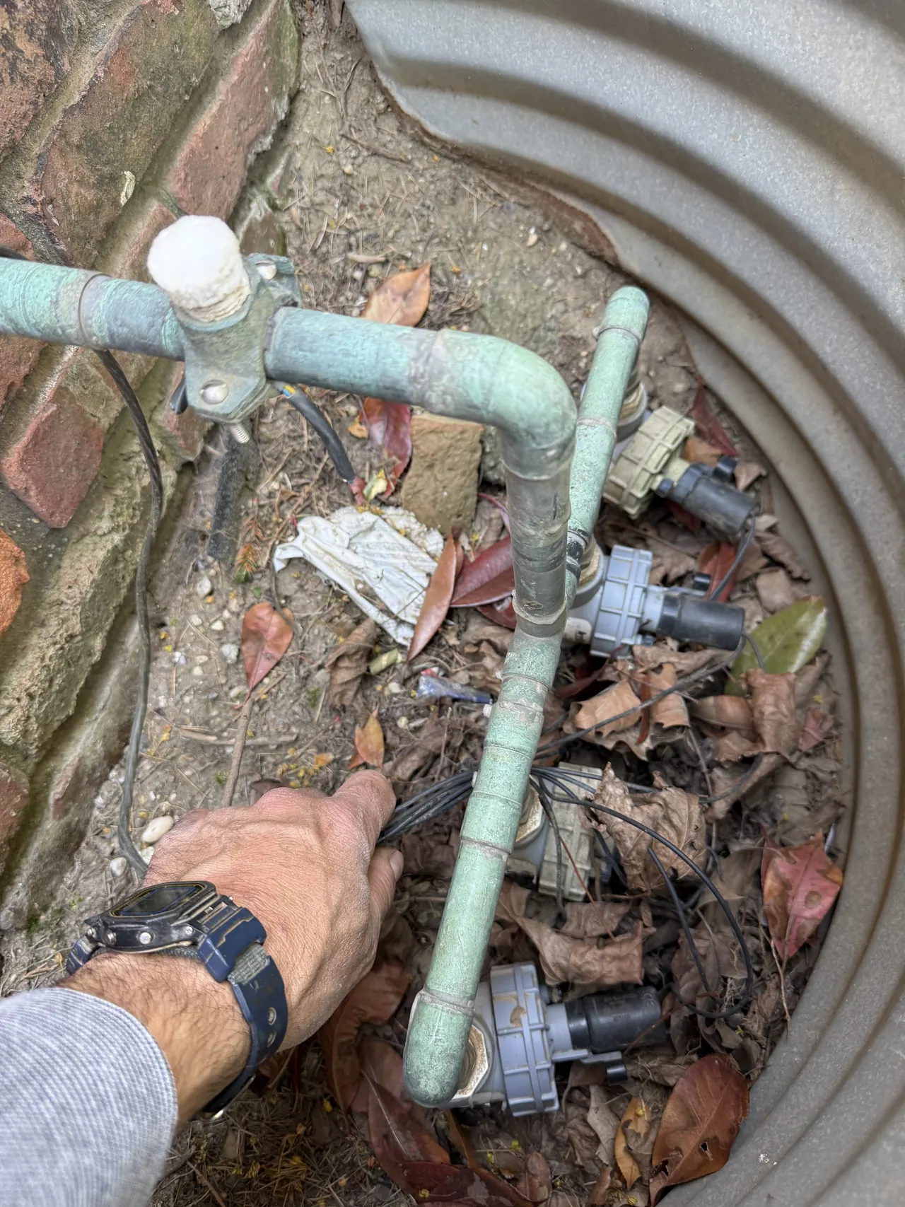 Copper manifold valve work and hand detail during sprinkler service