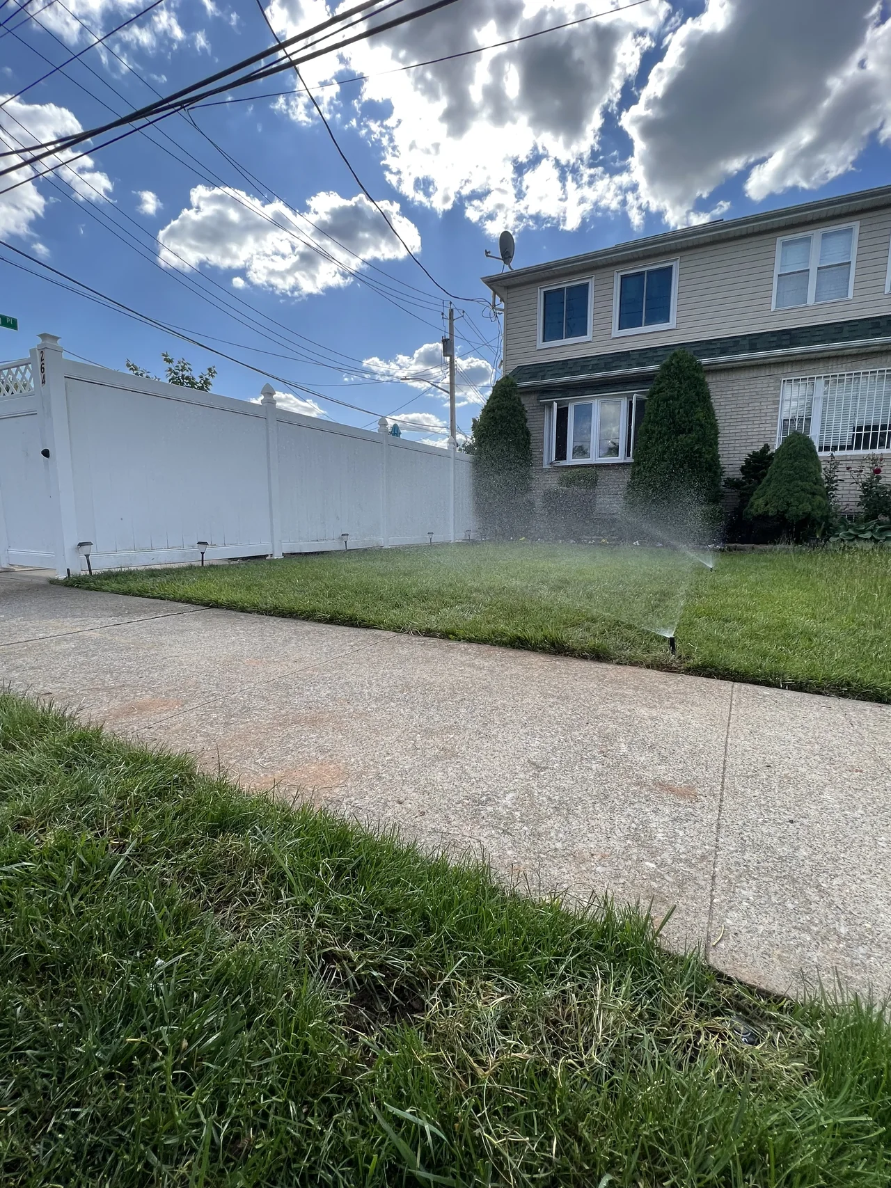 Sprinkler system watering a front lawn near a Staten Island home